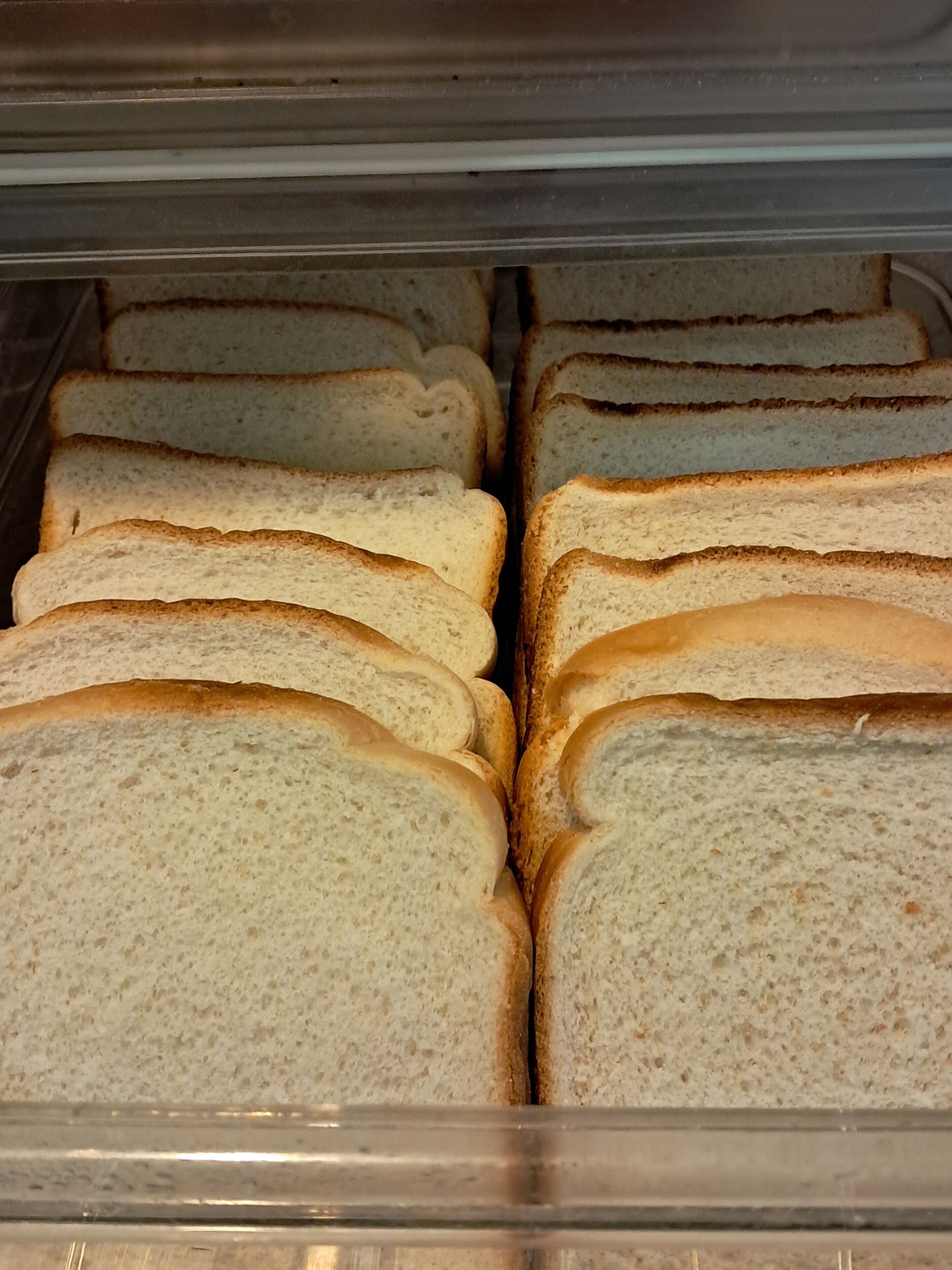 A clear view of a bread display case with multiple slices of bread arranged in rows.
