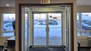 An indoor entrance with an EXIT sign above a revolving door leading outside. - Motel 6 Regina, SK (Regina)