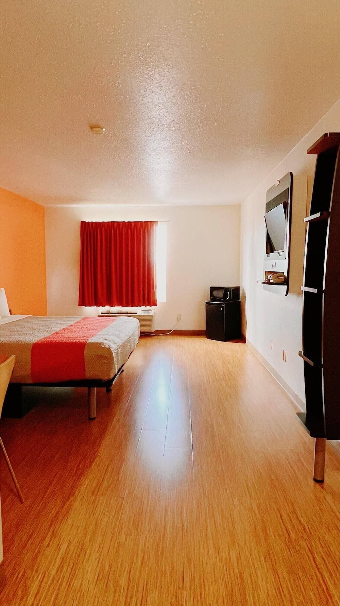 A spacious room with a large bed, a desk, a chair, a wardrobe, and a television.