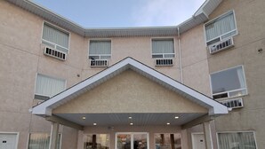 A multi-story building with a central entrance, large windows, and a snow-covered ground. - Motel 6 Regina, SK (Regina)