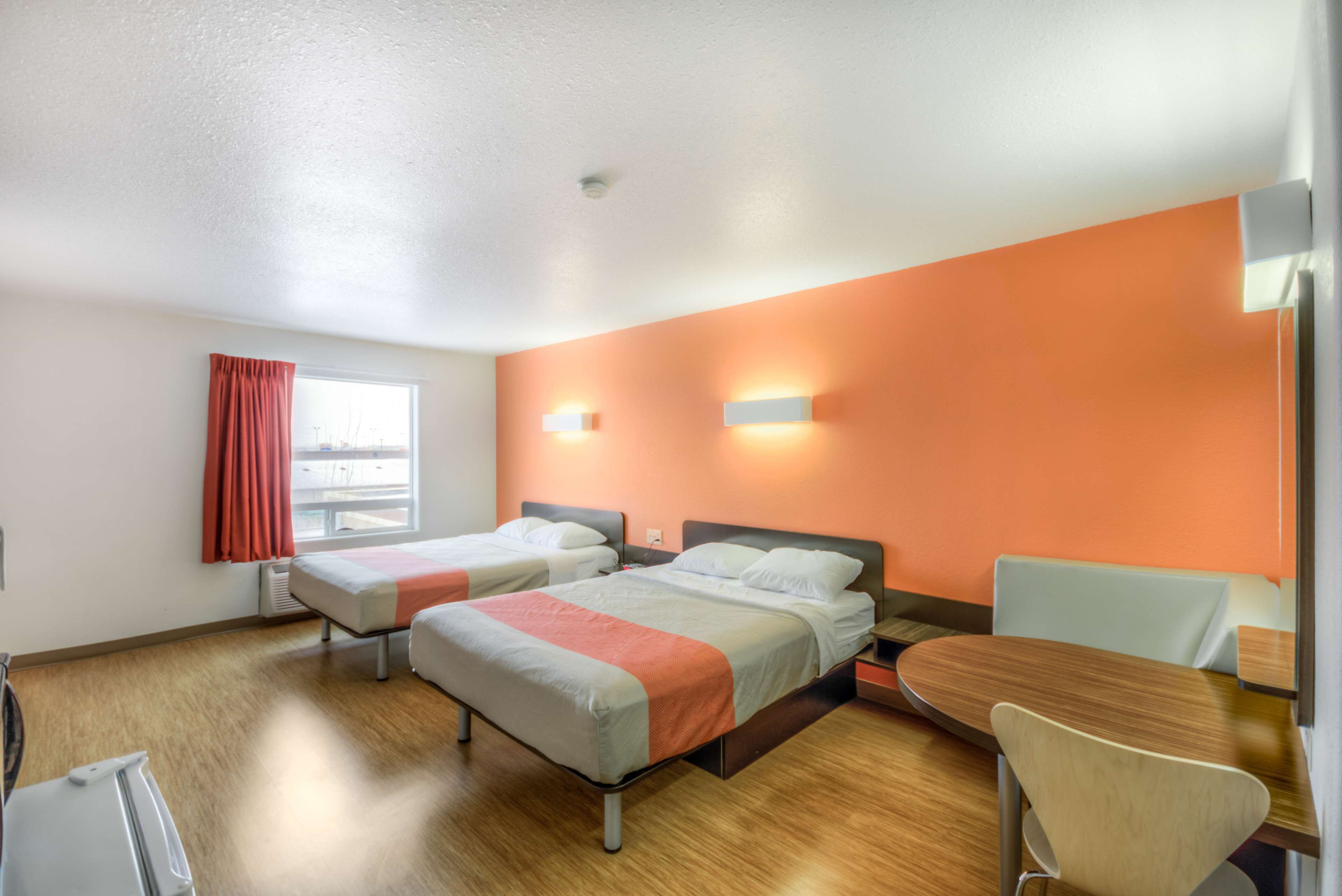 A hotel room with two beds, a dining table, and a chair.