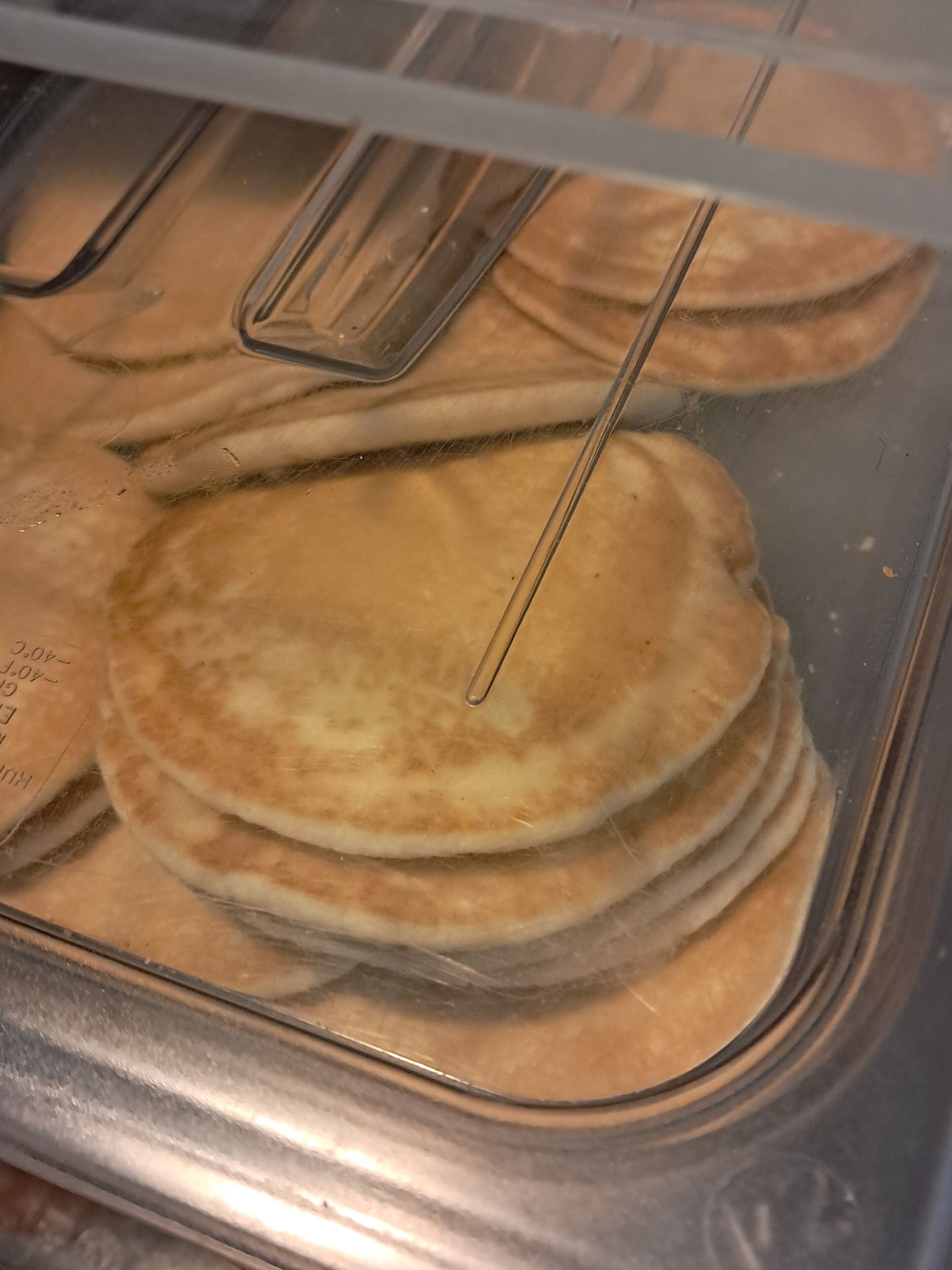 Un munt de crepes en un recipient de vidre amb una espàtula de metall.
