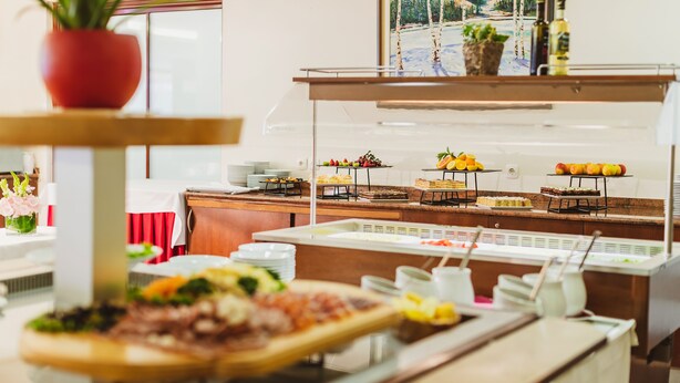 A buffet setup with various food items and a potted plant.