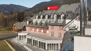 A modern hotel with a prominent sign, multiple balconies, and a view of mountains.