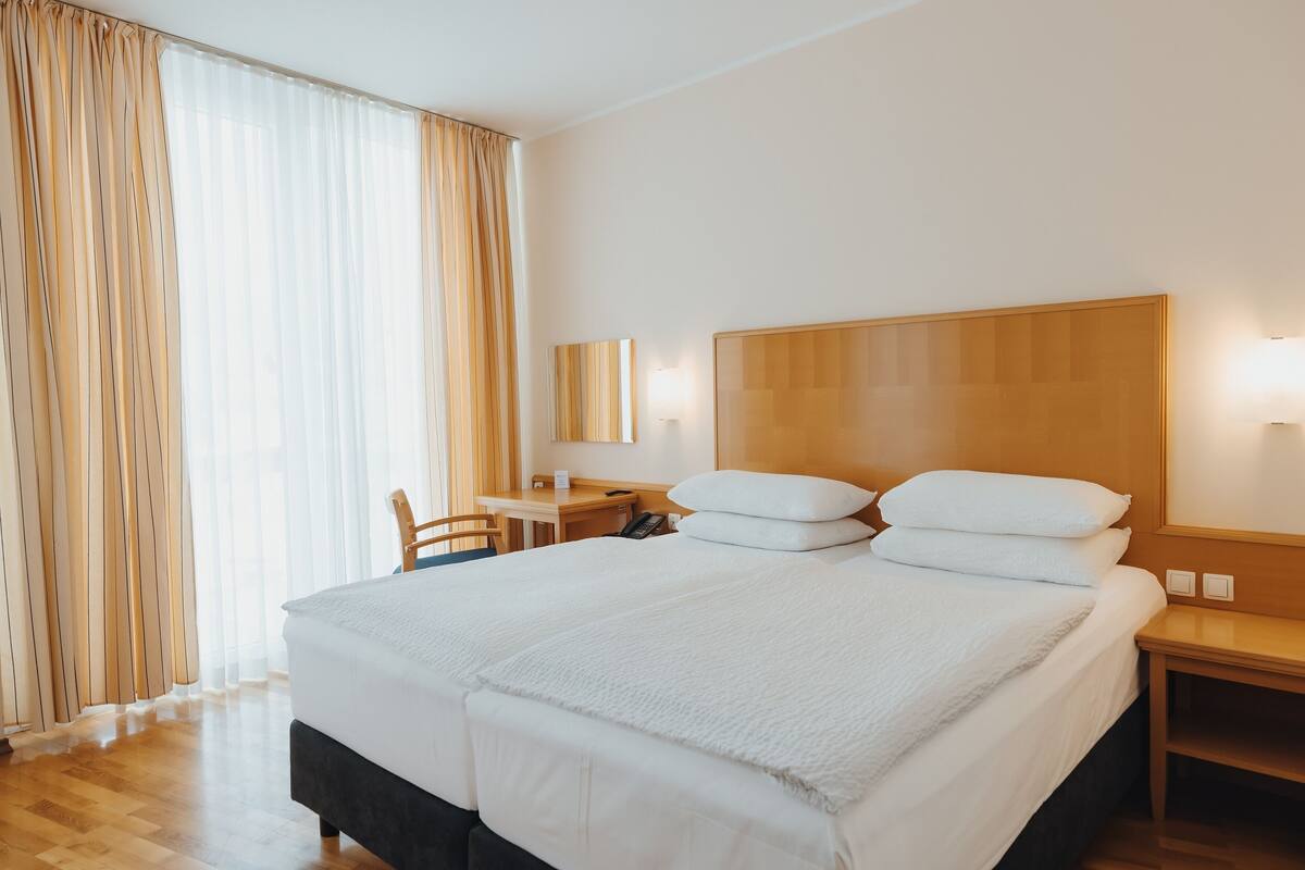 Una habitación de hotel con una cama grande, un escritorio, una silla y una mesita de noche.