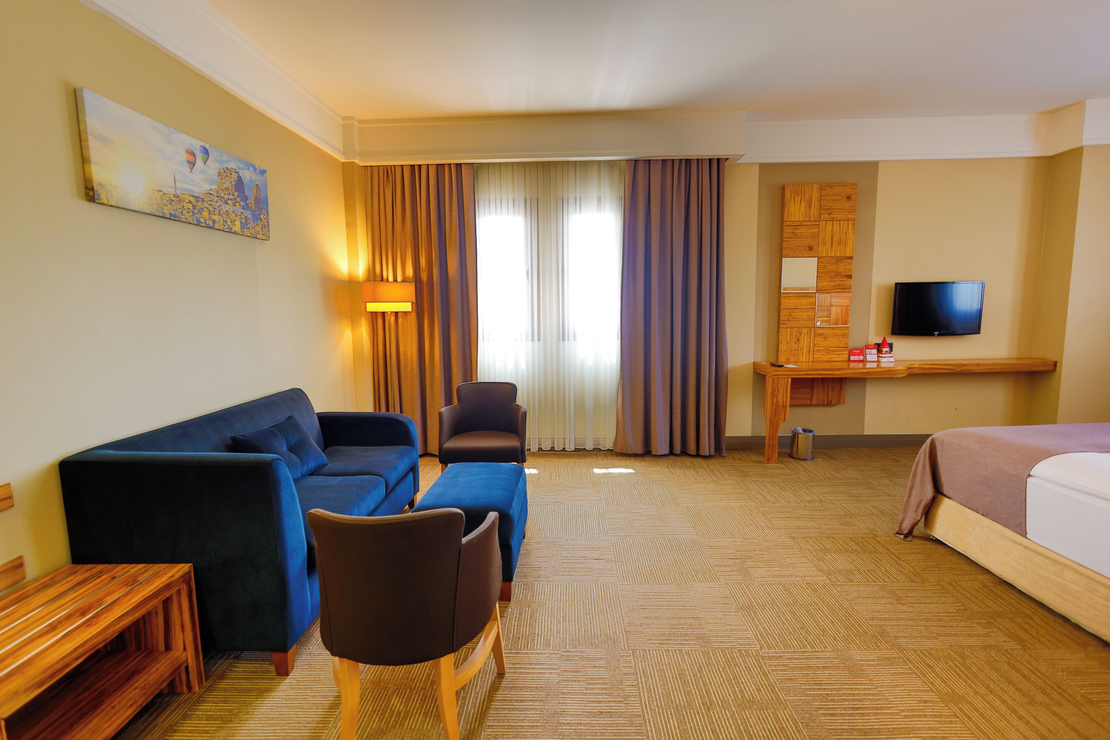 Una habitación de hotel con un sofá azul, un escritorio de madera, un televisor y una cama.