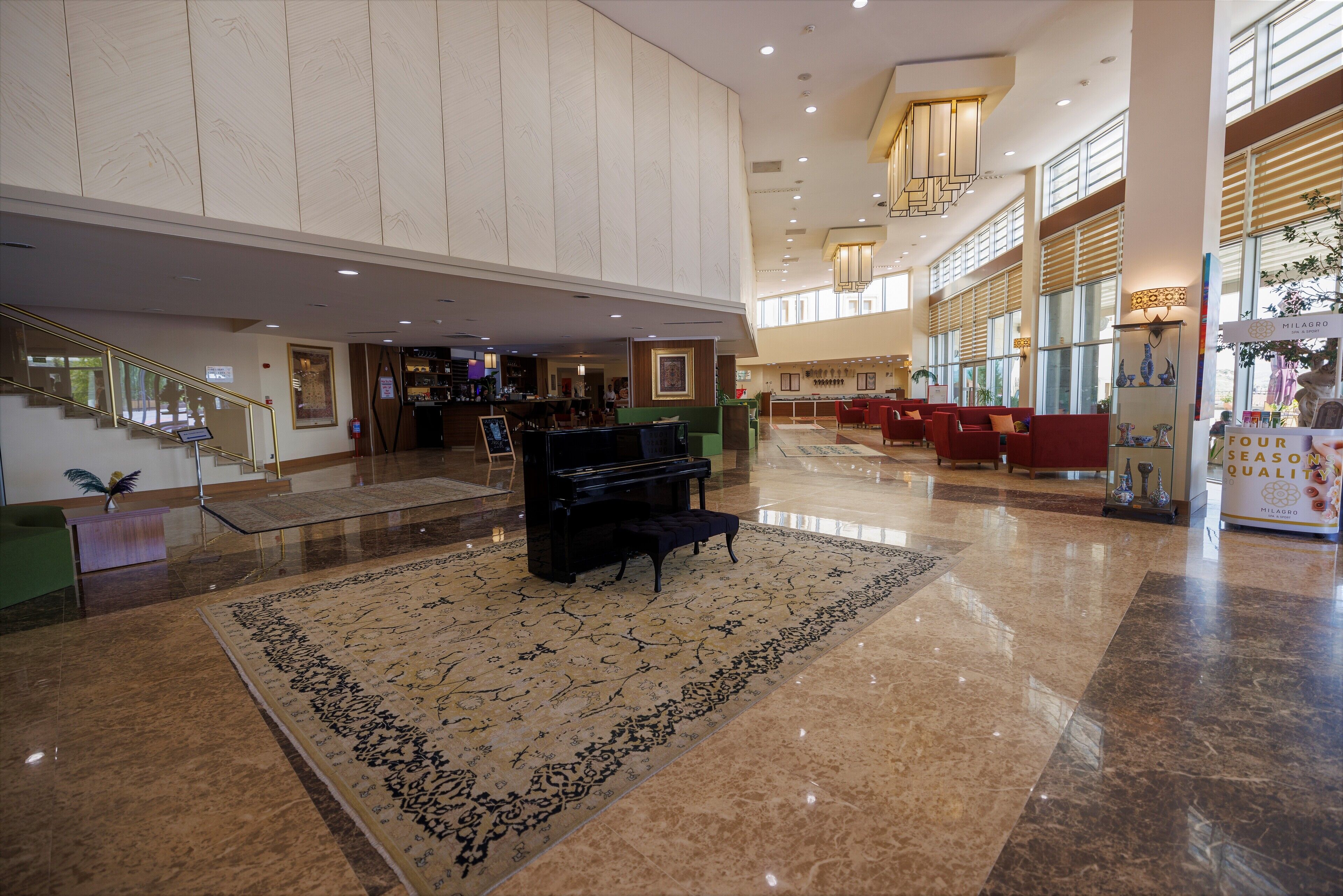 A spacious lobby with a grand piano, a large patterned rug, and a bar area.
