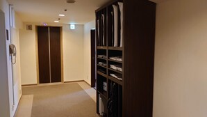 Een gang met een houten garderobe, een telefoon en een deur met een nummer.