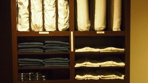 Een kast met netjes opgevouwen kleding en opbergdozen.