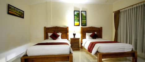 A hotel room with two wooden beds, white bedding, and a nightstand with a lamp.