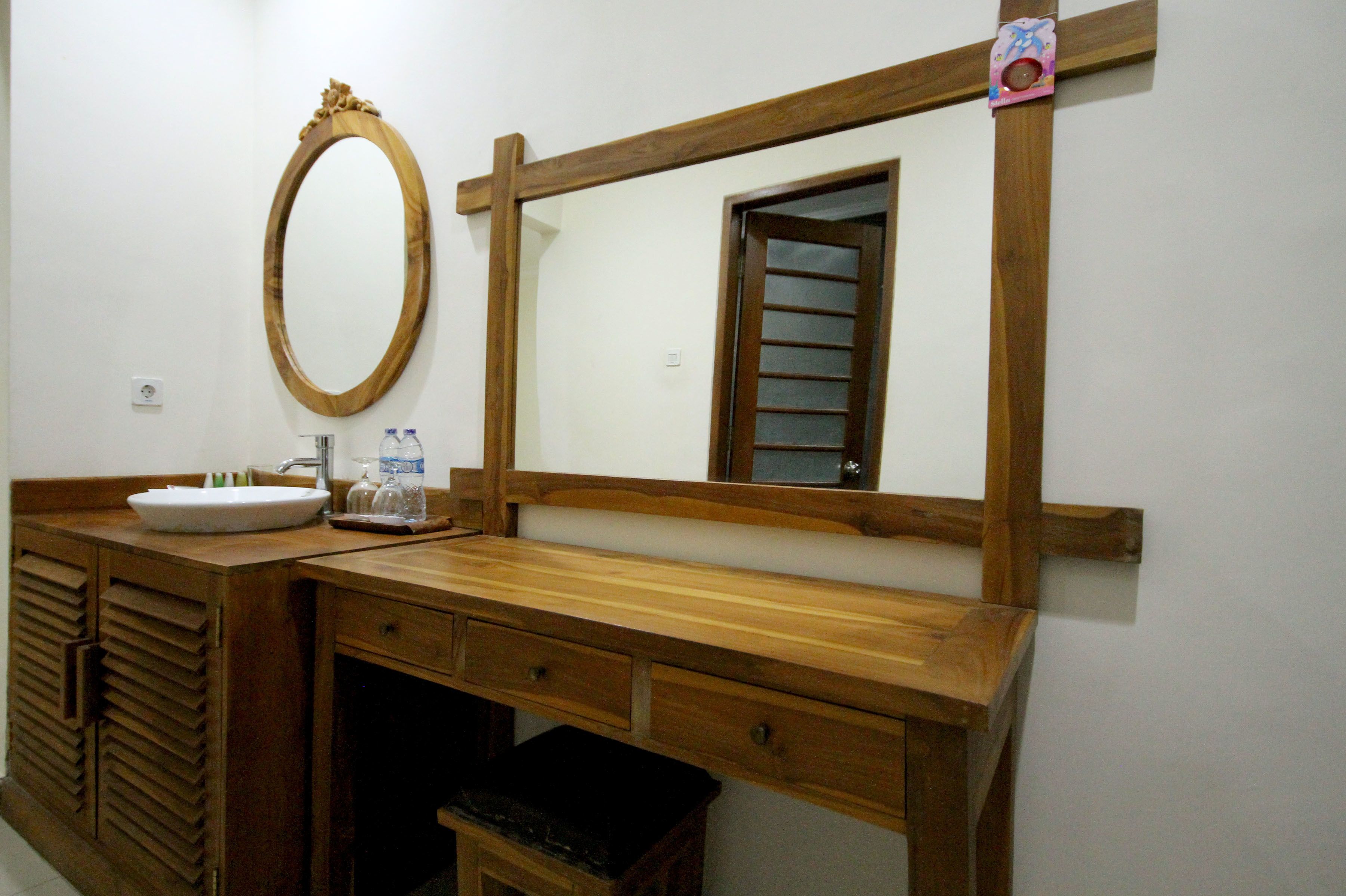 A wooden vanity with a mirror, a sink, and a small trash bin.