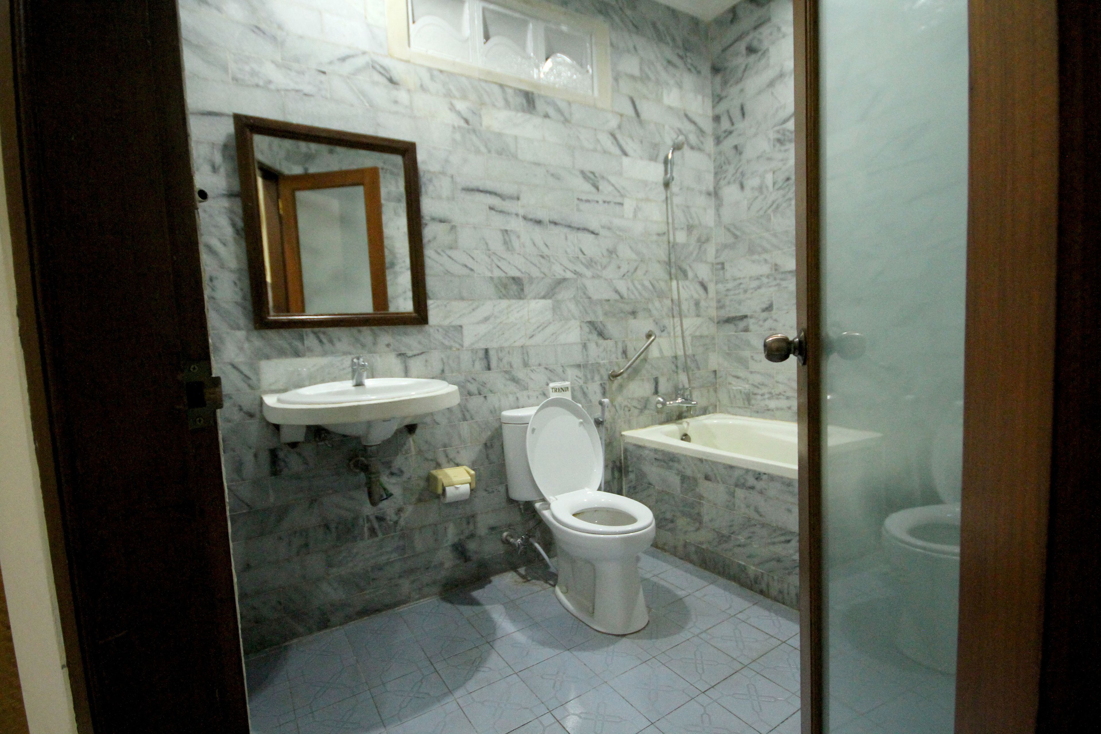 Et badeværelse med toilet, vask og badekar.