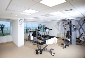 A gym with exercise equipment, a clock, and a window with a view of the ocean. - Brown Seaside Ashdod (Ashdod)