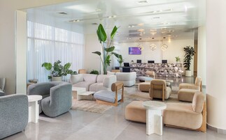 Un moderno vestíbulo de hotel con mostrador de recepción, zona de estar y amplias ventanas.