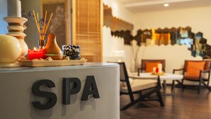 A reception area with a 'SPA' sign, a table with candles, and a decorative vase with reed sticks.
