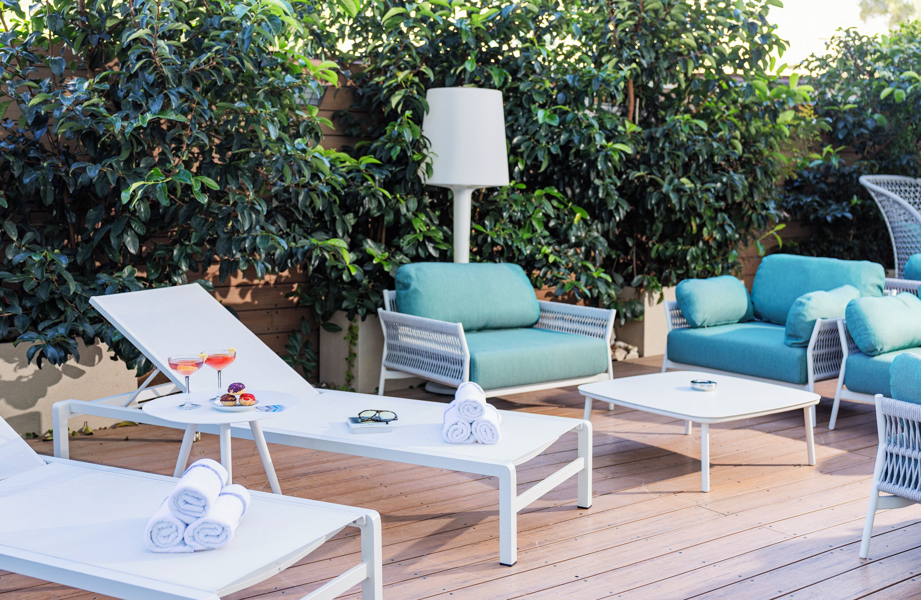 Een terras met witte lounge fauteuils, een witte tafel en een blauwe bank.