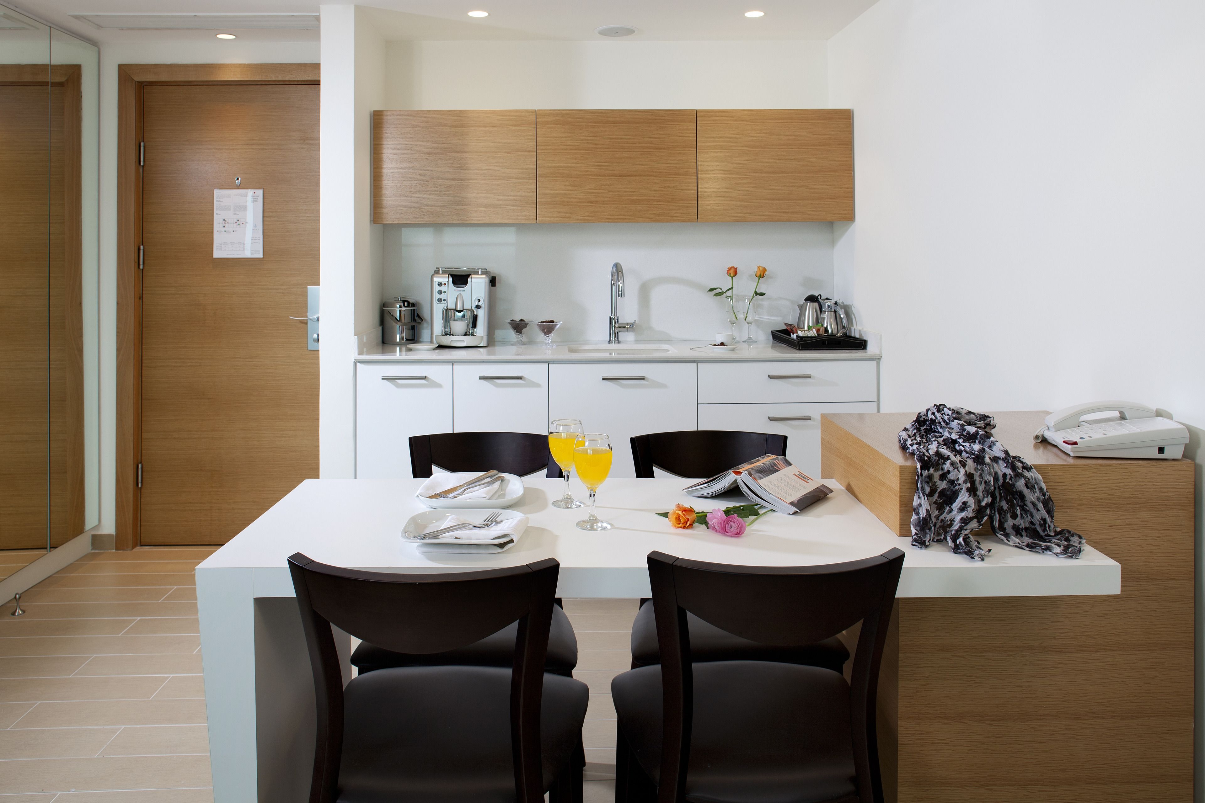 A modern kitchen with white countertops, wooden cabinets, and a central island with seating.