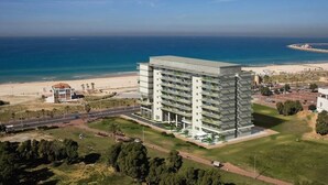 A modern multi-story hotel with a flat roof, located near a beach with a clear view of the ocean. - Brown Seaside Ashdod (Ashdod)