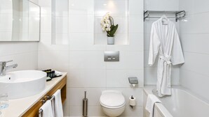 A modern bathroom with a sink, toilet, and bathtub. There is a towel rack and a mirror above the sink.