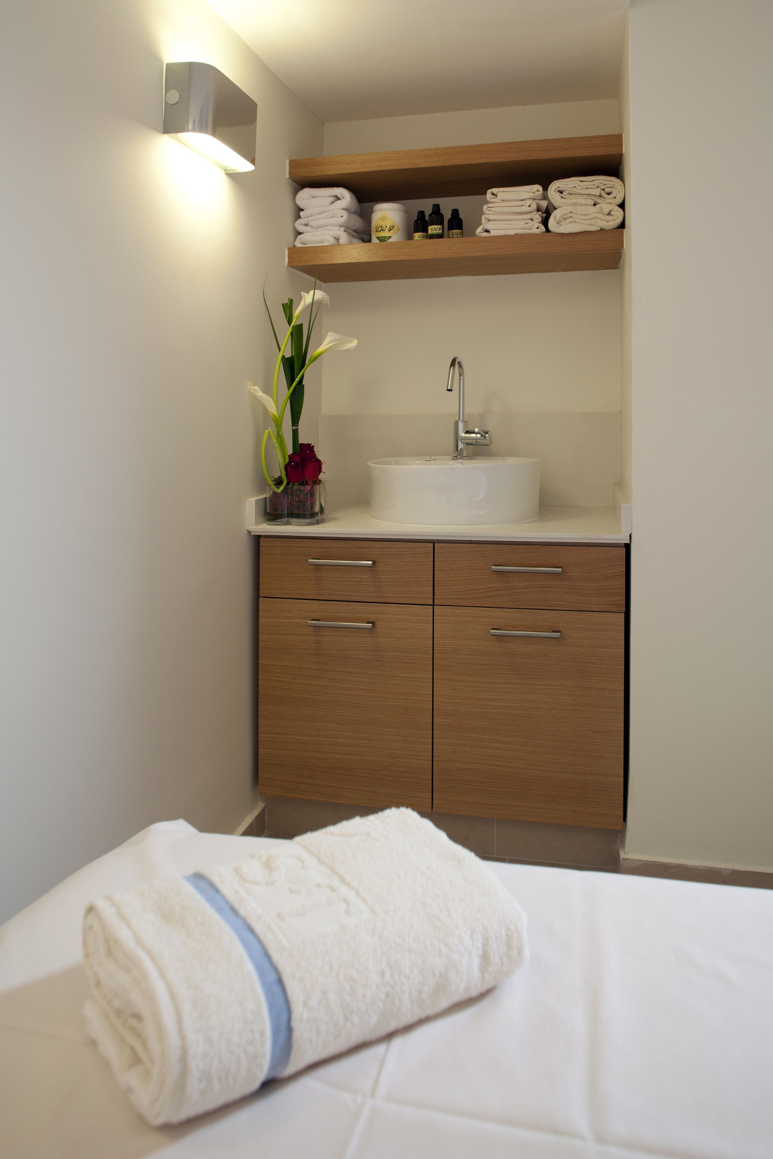 A bathroom with a sink, wooden cabinets, and a towel on the floor.