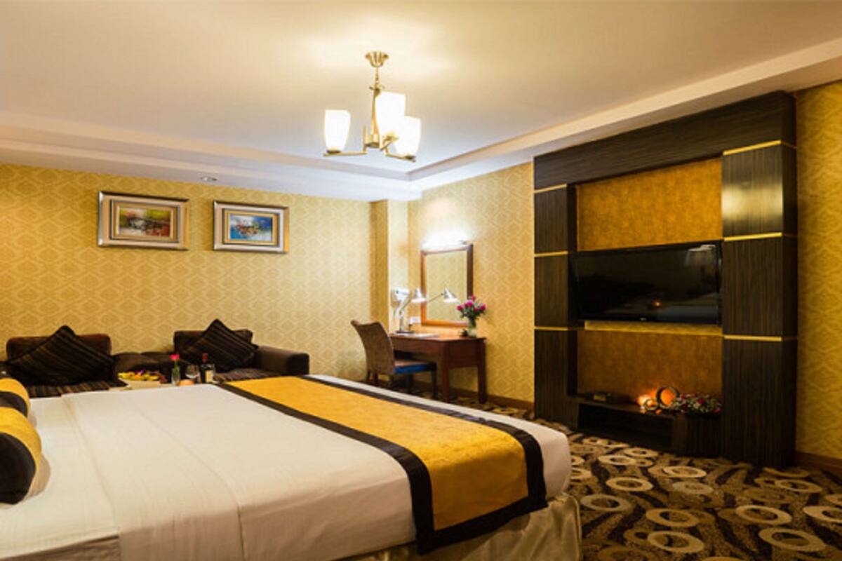 A hotel room with a large bed, a desk, a chair, a television, and a mirror.