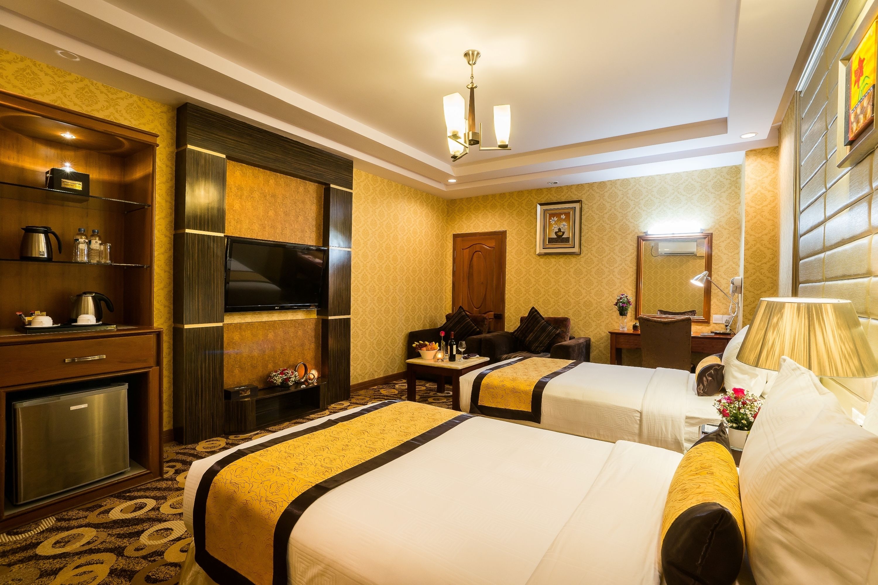 Een hotelkamer met twee bedden, een televisie, een bureau met lamp en een minibar.