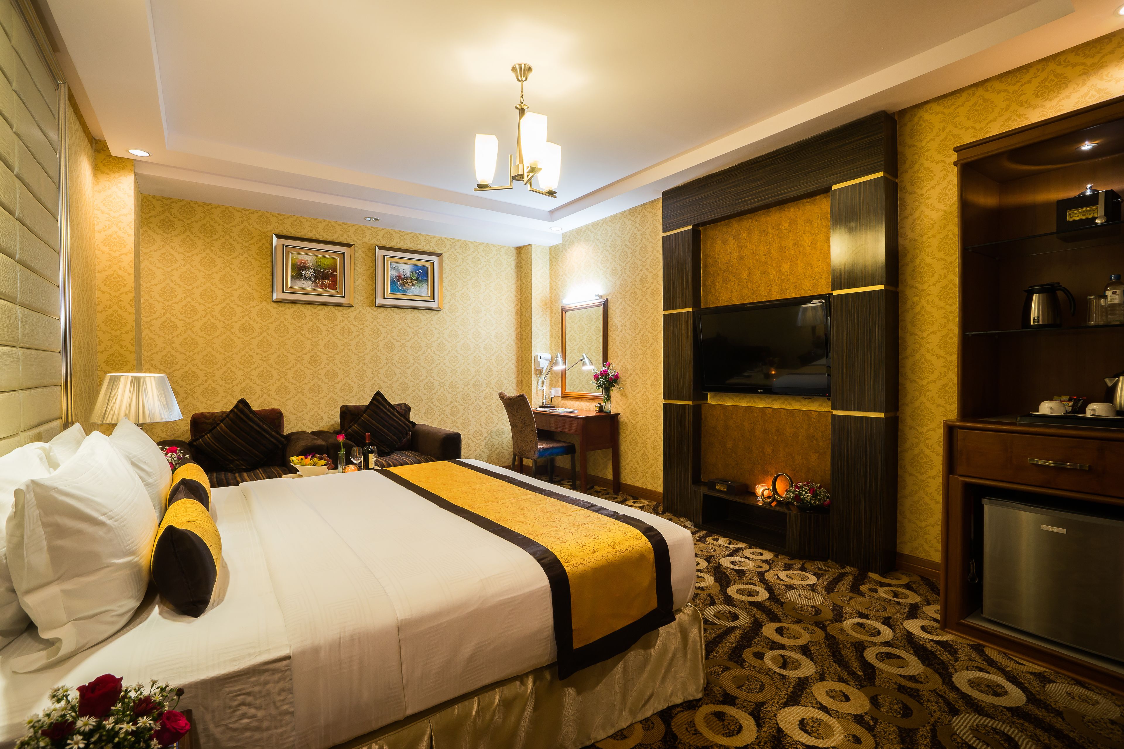 A hotel room with a large bed, a desk, a television, and a minibar.