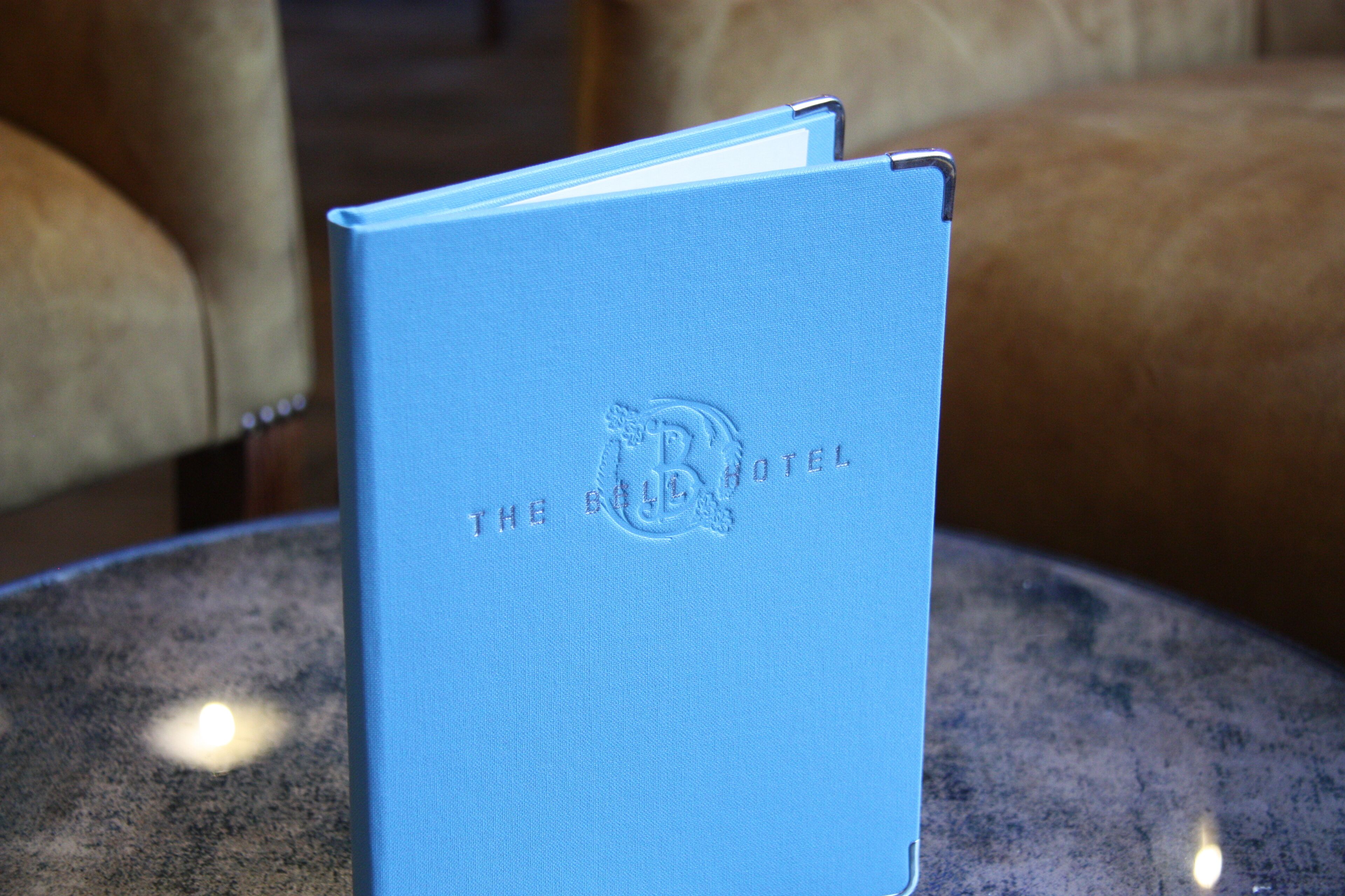 A blue book with embossed text and logo on its cover, placed on a round table.