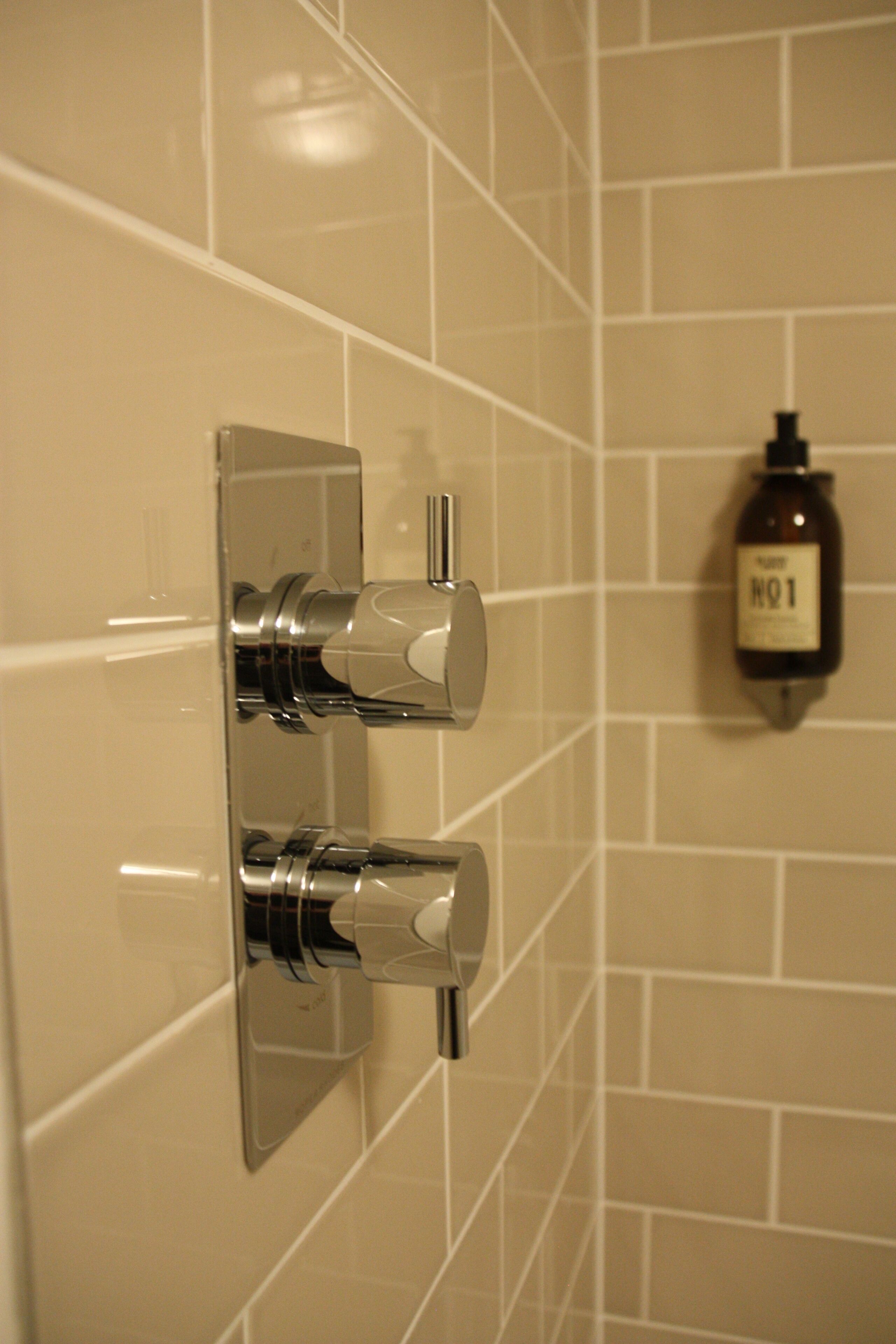 Een badkamer met een wandmengkraan en een fles handdesinfecterend middel met de tekst 'NO1'.