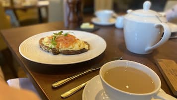 Una mesa con un plato de comida, una taza de té y una tetera.