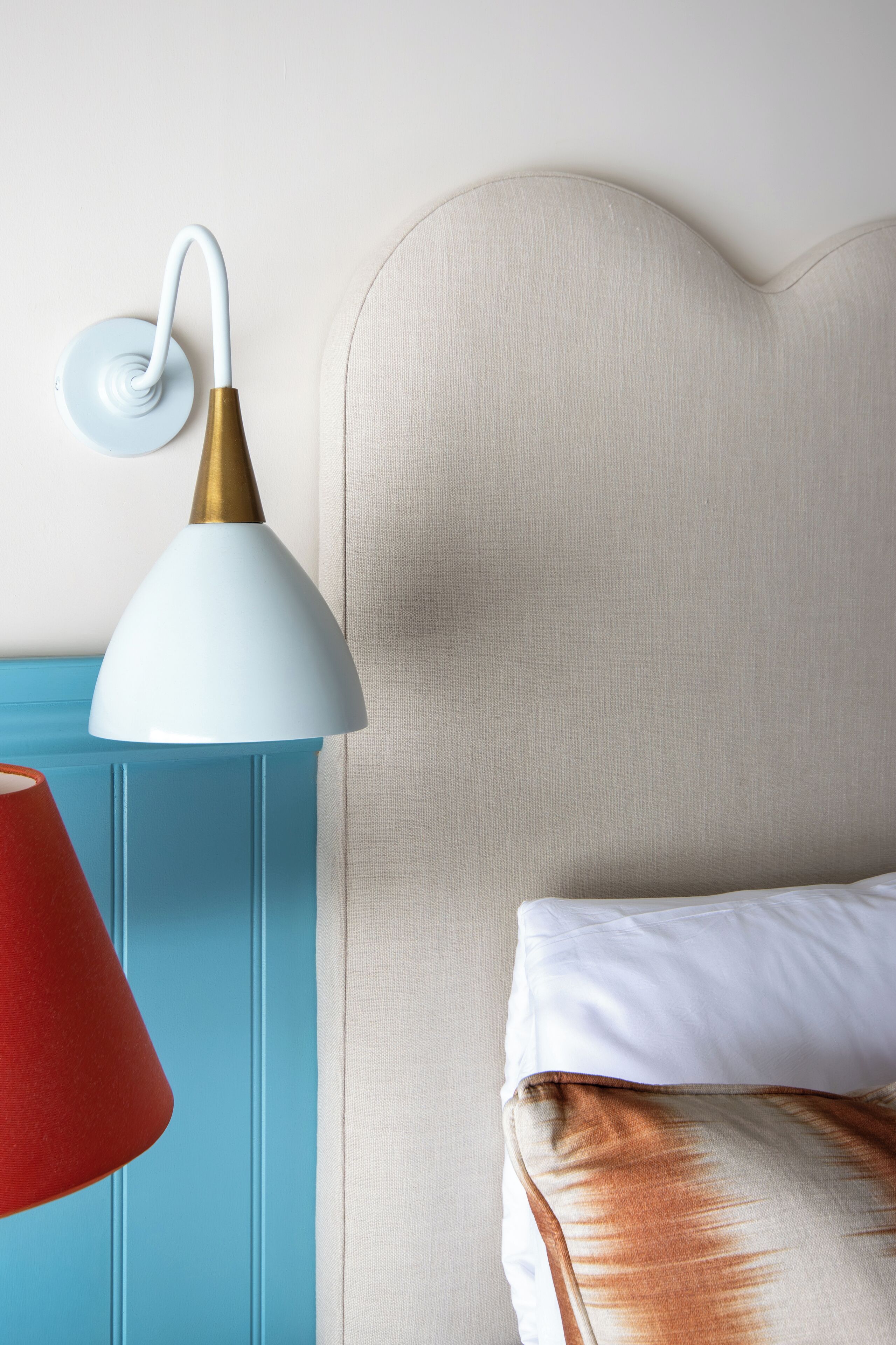 A bed with a white pillow and a beige headboard.