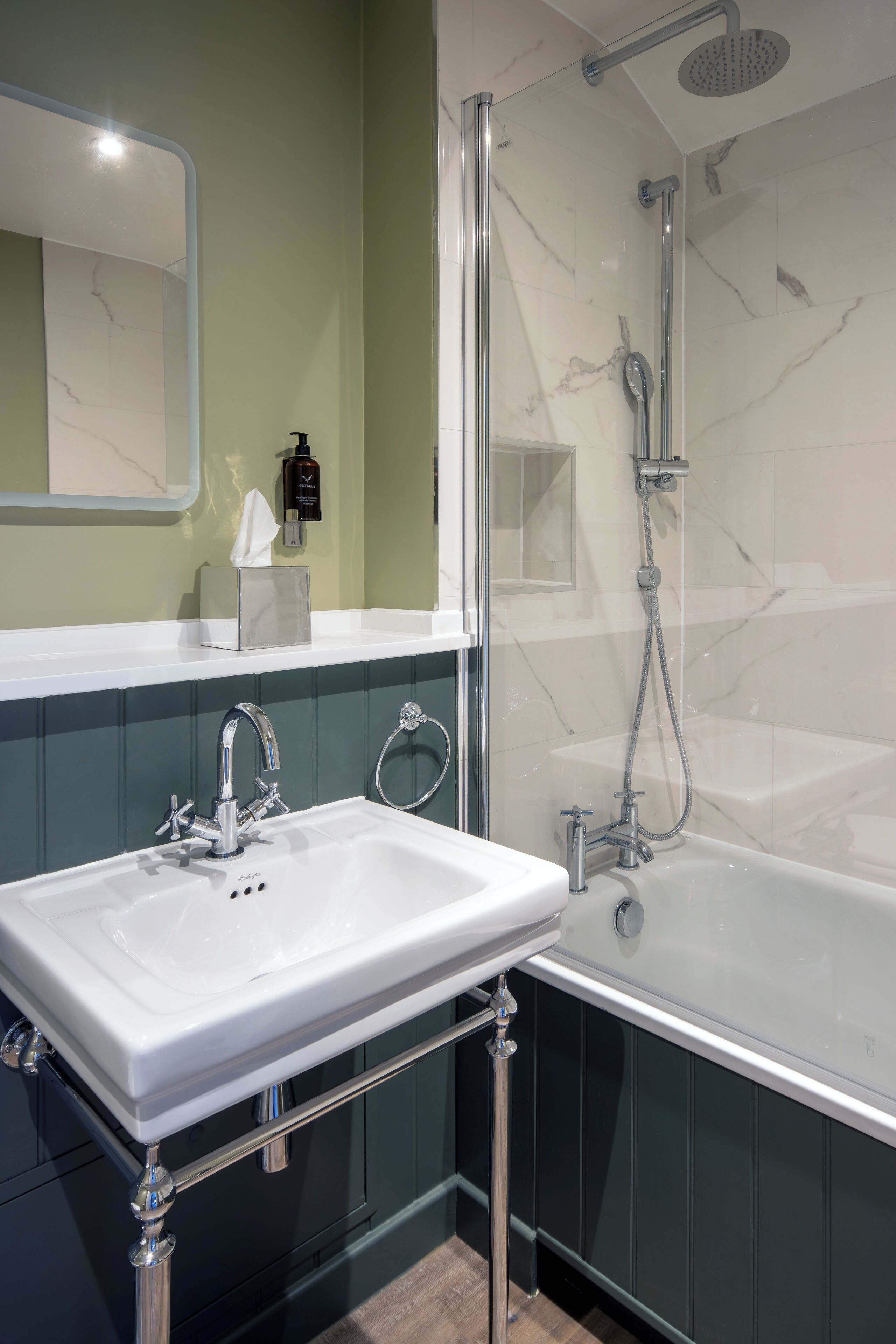 A bathroom with a white sink, a glass-enclosed shower, and a marble-tiled wall.