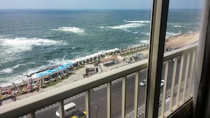 A coastal view from a balcony with a road, vehicles, and beachside umbrellas. - Royal Crown Hotel (Alexandria)