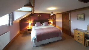 A bedroom with a bed, bedside tables, a desk, and a wardrobe.