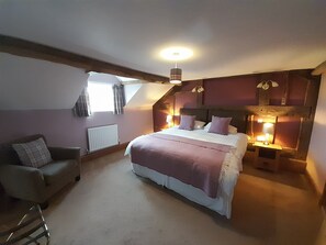 A bedroom with a bed, a chair, a radiator, and a window.