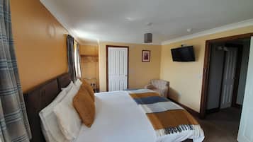 Una habitación de hotel con una cama, una silla, un televisor y una puerta.