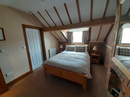 Un dormitorio con una cama de madera, dos mesitas de noche con lámparas, una pared de ladrillo y una ventana con cortinas.