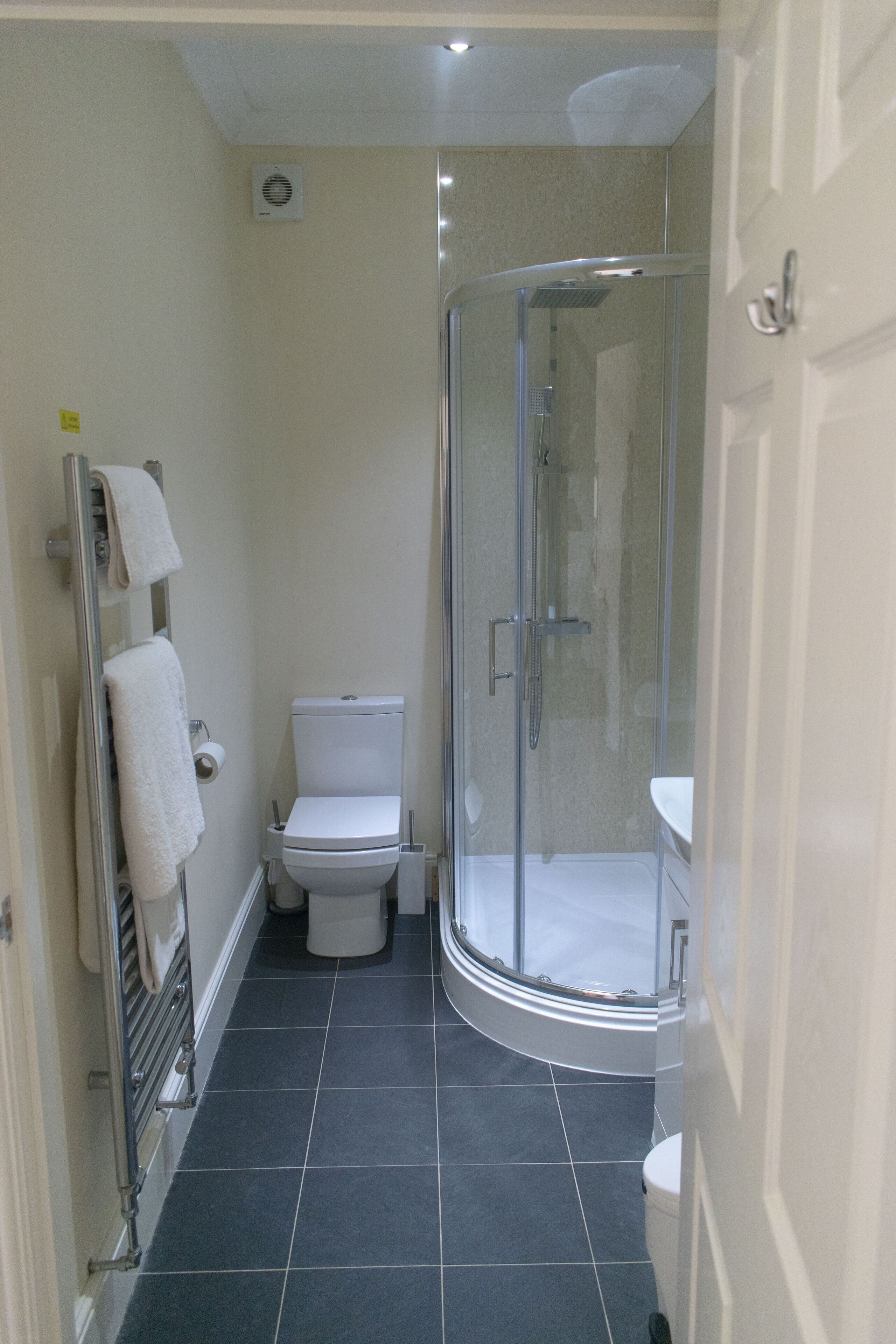 A bathroom with a glass-enclosed shower, a toilet, and a sink.