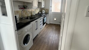 Una cocina con armarios blancos, lavadora y microondas.