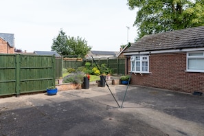 A residential area with a brick house, green fence, and potted plants. - The Lawns Guest House (Retford)