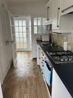 Una cocina con armarios blancos, encimera negra y suelo de madera.