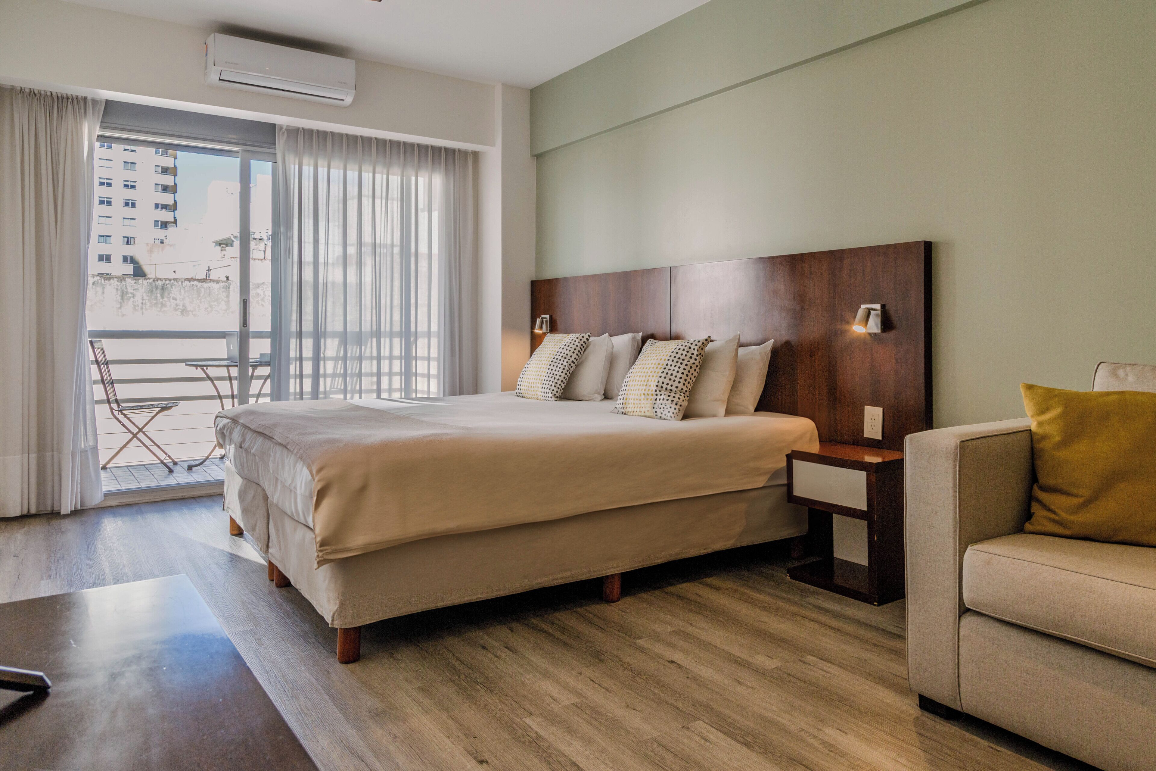 Habitació d'hotel amb un llit gran, un sofà, una taula petita i un balcó amb una cadira.