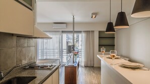 A modern kitchen with granite countertops, a built-in oven, and a dining area with a bar. - Color Botanico (Buenos Aires)