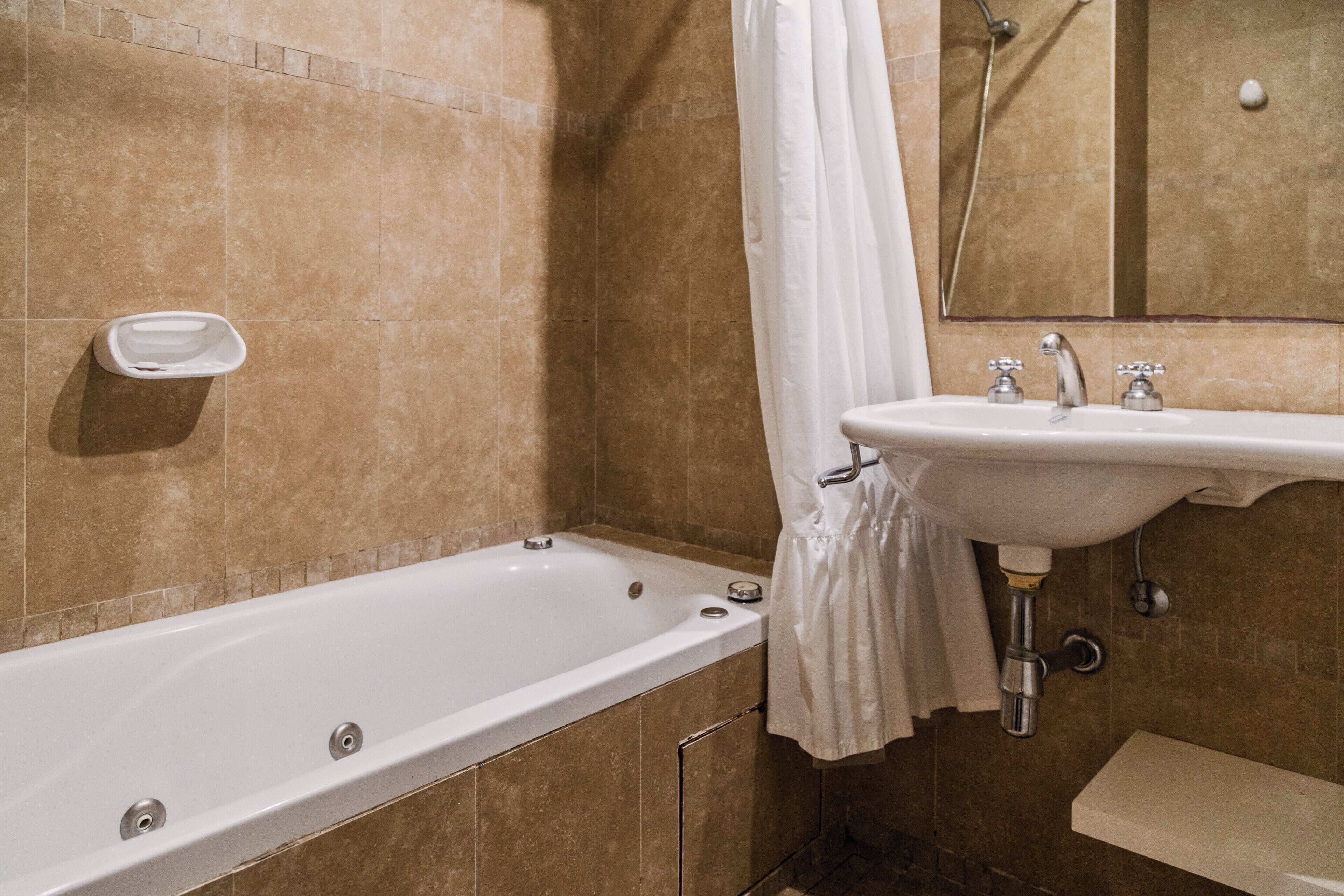 Un baño con bañera, lavamanos y espejo.