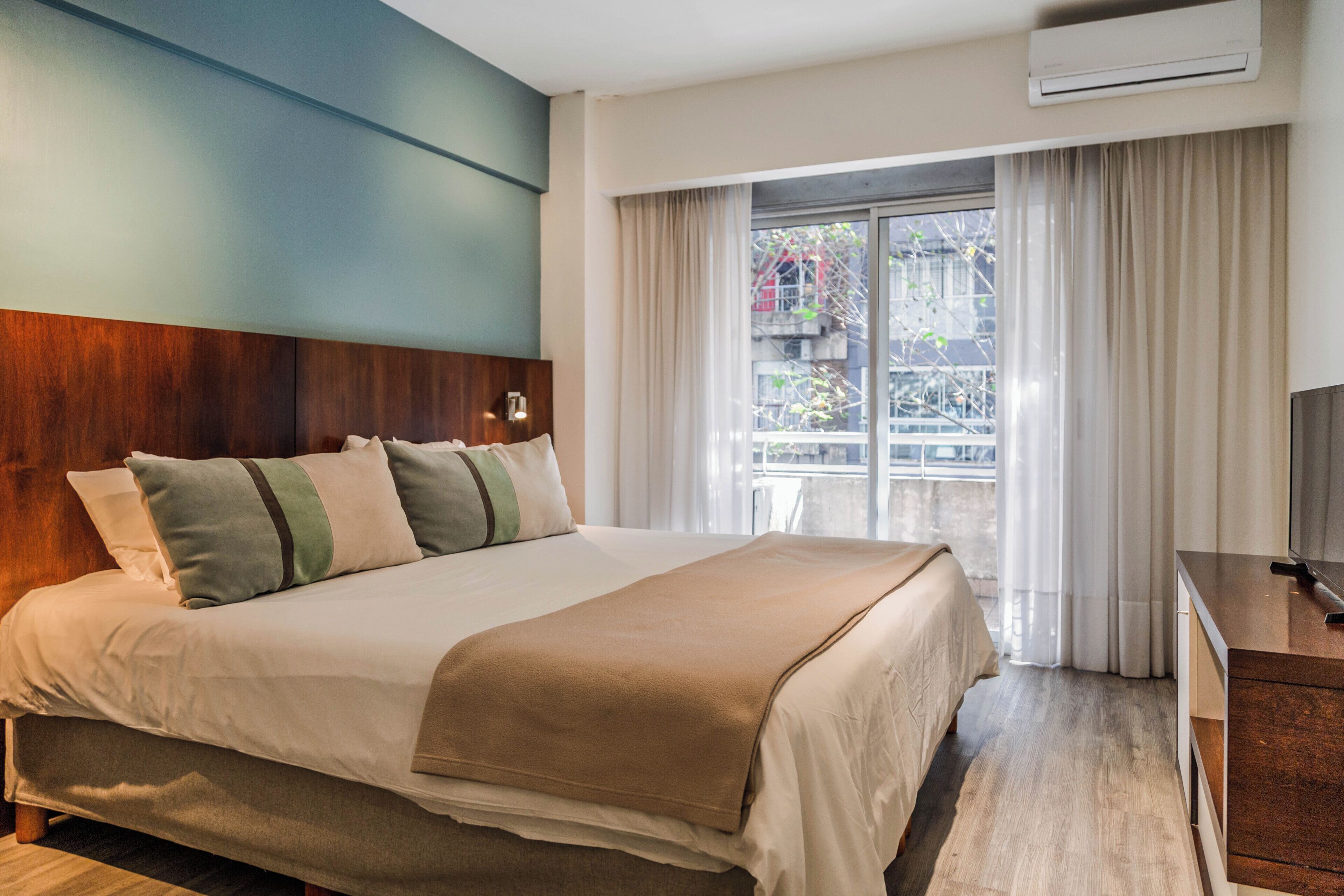 A hotel room with a bed, a desk, and a window with curtains.