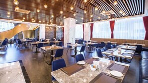 Een modern restaurant met hoge plafonds, hangende sferische lampen en een mix van eettafels en zitjes.