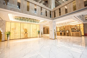 A spacious lobby with marble flooring, a reception desk, and a glass railing overlooking the lower level.