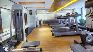 Een sportschool met loopbanden, een krachttrainingapparaat en een bank.