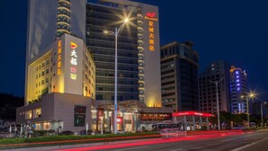 Een hotel met een moderne gevel, verlichte reclameborden en een opvallende entree.