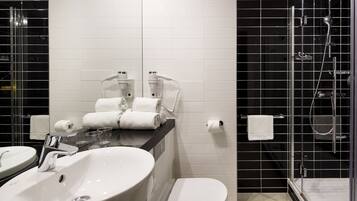 Un baño moderno con un lavamanos grande blanco, dos espejos, un inodoro y una zona de ducha con mampara de vidrio.